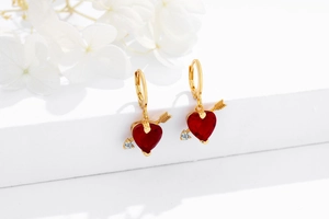 Vue macro de boucles d'oreilles en argent 925 doré avec pierre cœur rouge et flèche