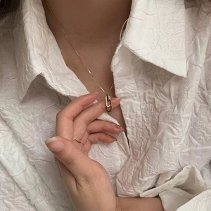 Close-up of interlocking gold pendant necklace with crystals on white textured shirt