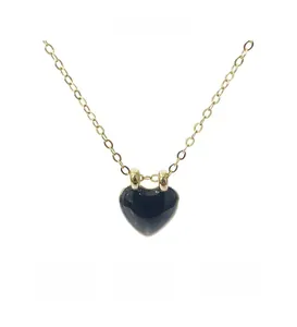 Détail d'un collier chaîne dorée minimaliste avec un pendentif cœur noir poli