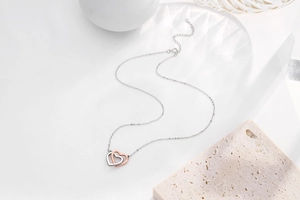 Detailed view of intertwined silver and rose gold double heart pendant with fine O-chain