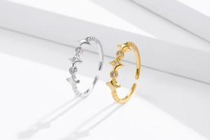 Adjustable silver and gold star rings with sparkling zircon accents on white stairs