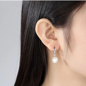 Elegant S925 sterling silver drop earrings with lustrous round white pearls on model