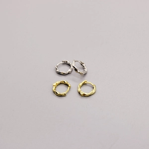 Detailed view of minimalist twisted metal hoop earrings in gold and silver finishes