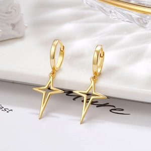 Vue macro de boucles d'oreilles créoles dorées avec pendentifs en forme d'étoile évidée