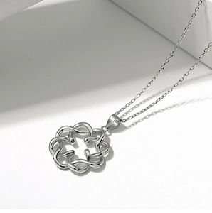 Macro detail of a 925 sterling silver bow pendant with a polished mirror finish on a chain