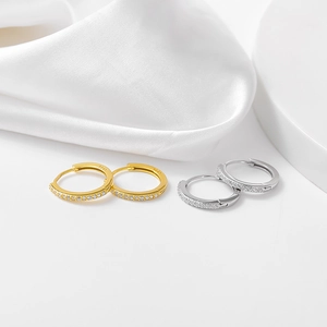 Dettaglio di orecchini huggie in argento S925 con cristalli pavé in oro e argento