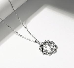 Macro shot of 925 sterling silver interlocking circle bow pendant necklace on white base