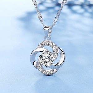 Vue macro d'un pendentif trèfle à quatre feuilles en argent serti de zircons sur fond bleu clair
