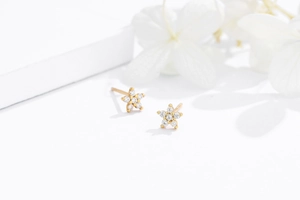 Macro shot of 925 sterling silver six-prong flower studs with sparkling white zircons