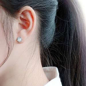 Close-up of elegant six-prong crown stud earrings with round-cut zircon on female ear
