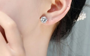 Close-up of classic six-prong crown stud earring with brilliant round-cut moissanite stone