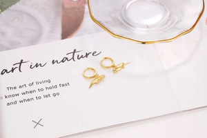 Macro detail of bird-shaped gold earrings with S925 sterling silver hallmark stamp