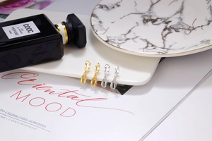 Close-up of gold and silver S925 sterling silver shell drop earrings on a white display