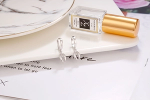 Detail of silver S925 shell hoop earrings on ceramic tray with elegant lifestyle decor
