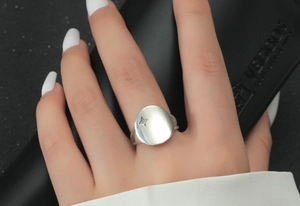 Close-up of S925 silver oval signet ring with engraved star and cubic zirconia on model