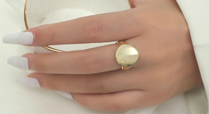Detail of a minimalist gold round signet ring featuring a delicate starburst stone setting