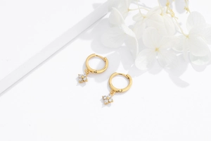 Macro shot of gold-plated S925 silver hoop earrings with four-petal zircon flower charms