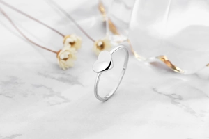 Detail of s925 silver heart ring on marble surface with minimalist aesthetic background