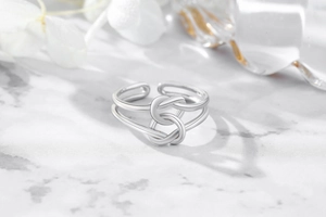 Detailed close-up of double-layer silver bow ring on elegant marble background