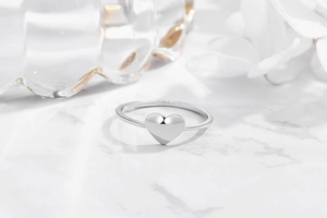 Close-up of minimalist S925 sterling silver heart ring on a white marble background