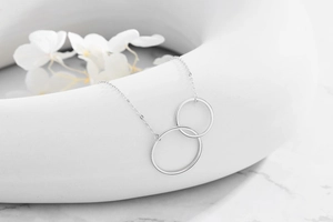 Close-up of interlocking double circle silver necklace on an elegant marble background