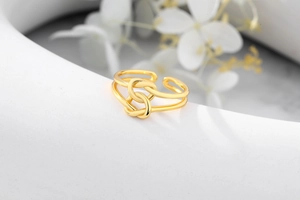 Macro view of gold knotted double-layer open ring on an artistic white pedestal