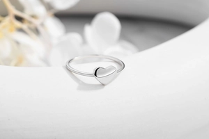 Detailed view of polished S925 sterling silver heart ring on a white artistic display