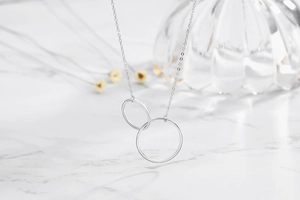 Close-up of interlocking S925 sterling silver double circles necklace on marble
