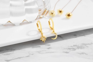 Makroaufnahme der asymmetrischen Stern- und Mondohrringe in Gold mit Zirkonia