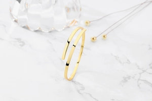 Close-up of golden S925 sterling silver layered open bangle with engraved hallmark