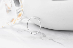 Macro detail of s925 silver heart ring showing fine polished band on marble background