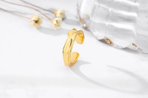 Detail of 925 sterling silver gold plated Mobius ring with lava texture on marble