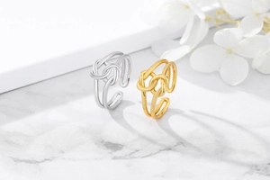 Close-up of double-layered knot rings in gold and silver on a marble surface