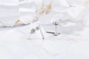 Macro shot of S925 sterling silver geometric earrings with zircon studs on marble background
