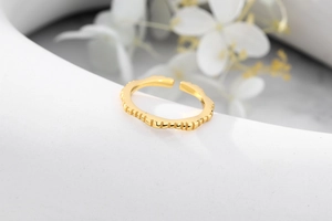 Close-up of golden adjustable ring with vertical texture on a white decorative plate