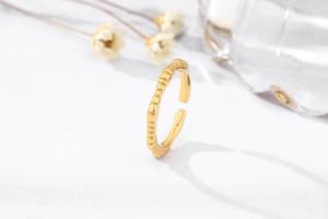 Detail of golden adjustable ring with unique textured surface and polished finish
