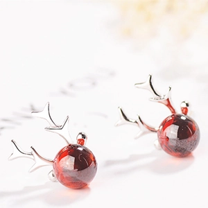 Macro detail of S925 silver reindeer earrings with translucent red garnet stone