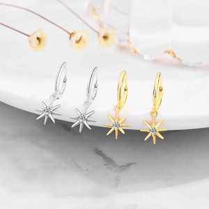 Detailed macro of gold and silver S925 sterling silver star-shaped dangle hoop earrings