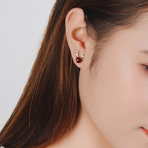 Detail of 925 sterling silver reindeer antler stud earring with red stone on model