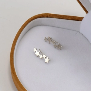 Macro view of minimalist S925 sterling silver star crawler earrings on white velvet