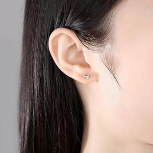 Boucles d'oreilles boules minimalistes en argent 925 portées par un mannequin chic