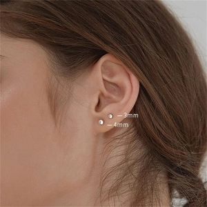 Vue macro de boucles d'oreilles boules en argent 925 poli de 3mm et 4mm sur l'oreille