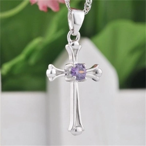 Close-up of silver cross pendant with central purple crystal inlay and rounded ends