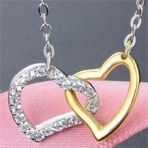 Macro shot of interlocking silver and gold hearts necklace with sparkling cubic zirconia