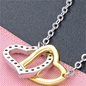 Macro shot of interlocking silver and gold hearts with cubic zirconia on a chain