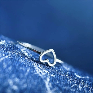 Vue macro d'une bague coeur en argent sur un fond bleu foncé scintillant