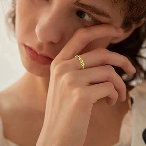 Detailed view of a gold spiral ring with rotating beads worn on a model's finger