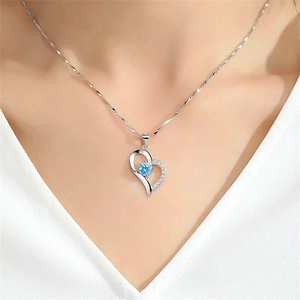 Close-up of S925 silver heart necklace with blue zircon pendant worn on model neck