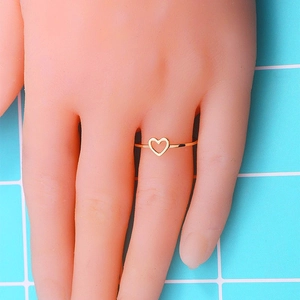 Détail d'une bague en or en forme de cœur minimaliste portée au doigt