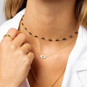 Detailaufnahme der mehrlagigen goldenen Evil Eye Halsketten und passender Stern-Ringe